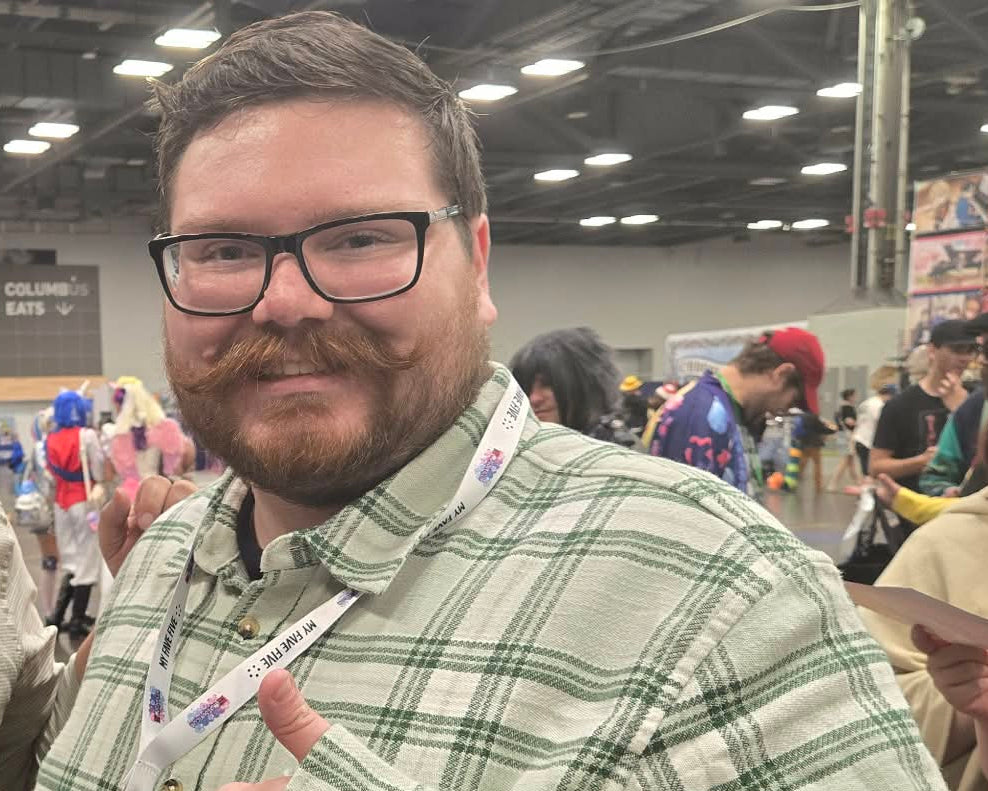 Husband of the artist, Cody Goodwill, smiling and giving a thumbs up.